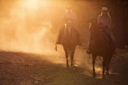 Cowgirls riding through the dust at a horse photography workshop