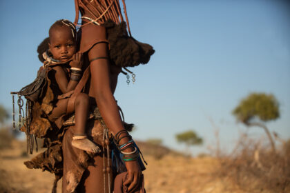 Angola, Himba young mother caring baby on back.